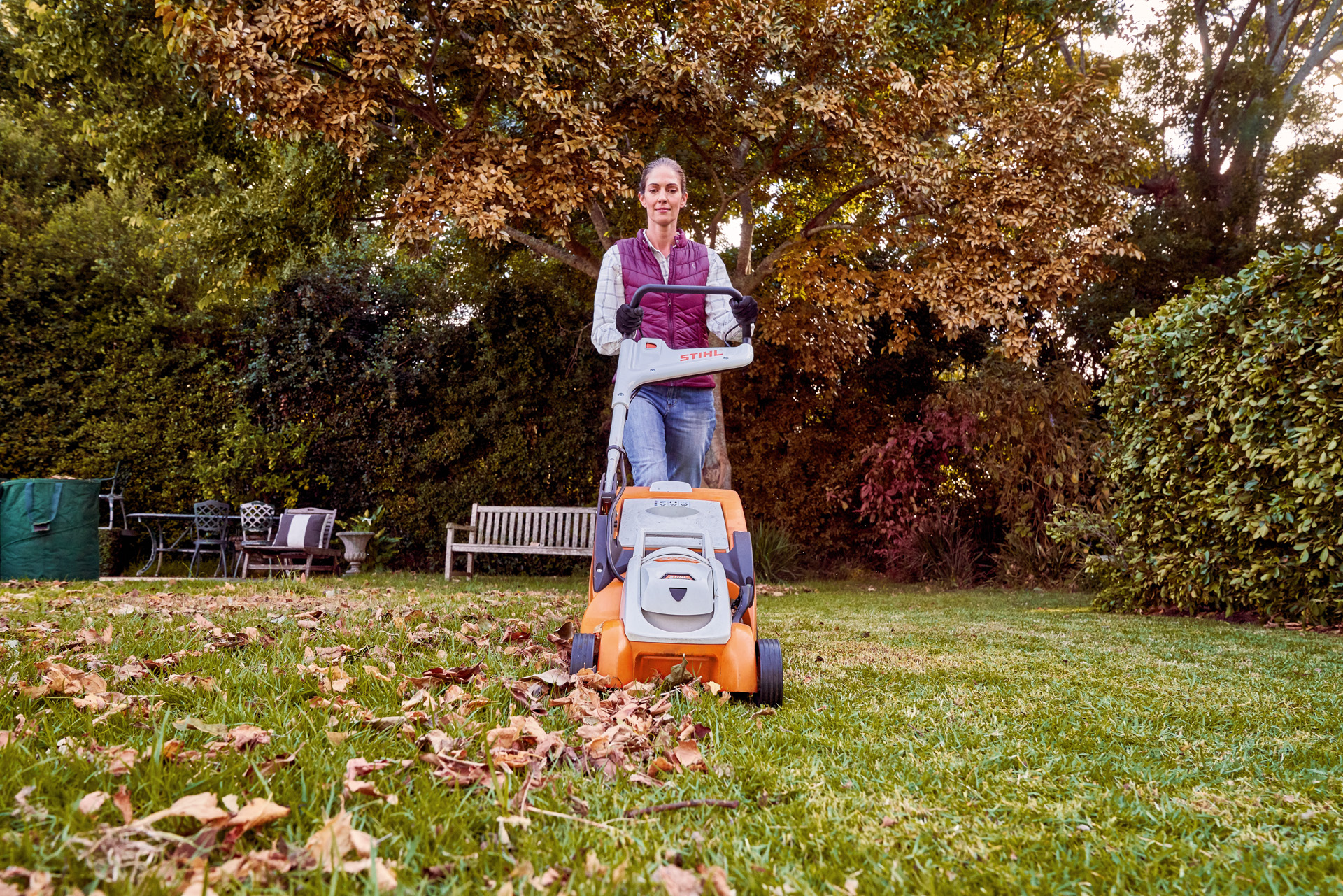  Kobieta używająca kosiarki akumulatorowej STIHL RMA 339 C w ogrodzie do jesiennej pielęgnacji trawnika