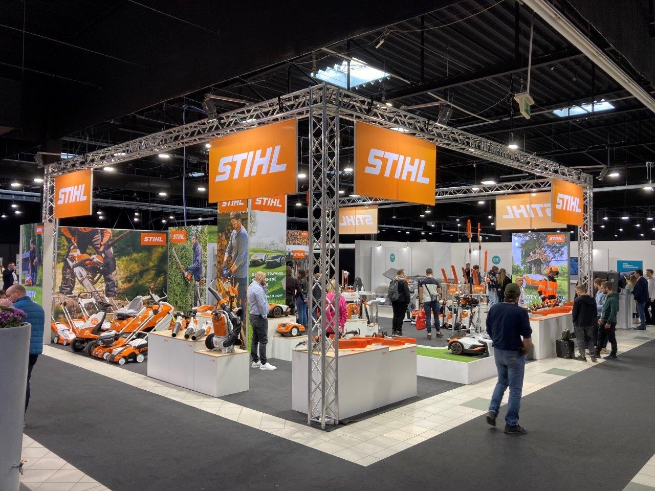 Besucher des STIHL Messestandes schauen sich Produktneuheiten an, darunter eine STIHL Motorsäge 