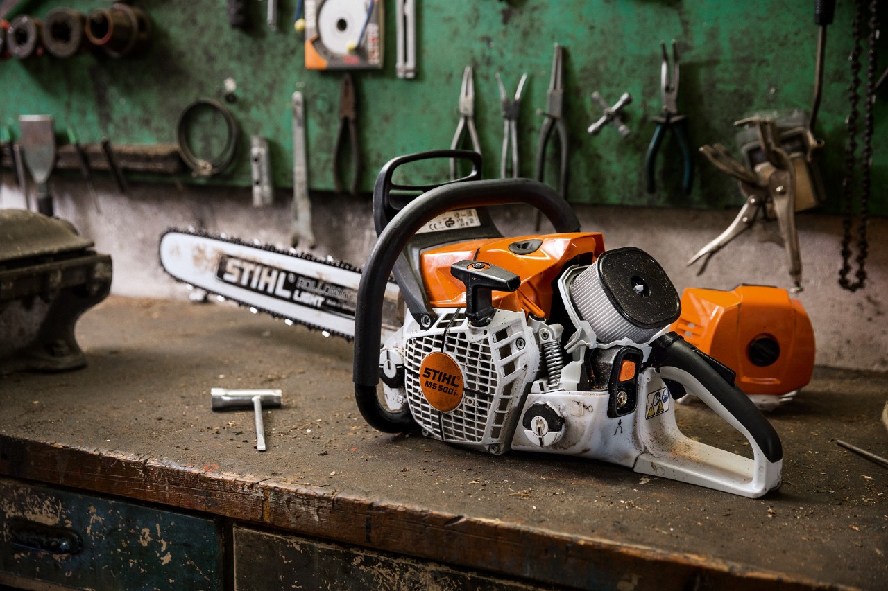 Pilarka spalinowa STIHL MS 500i W na stole warsztatowym z narzędziami wiszącymi na ścianie z tyłu