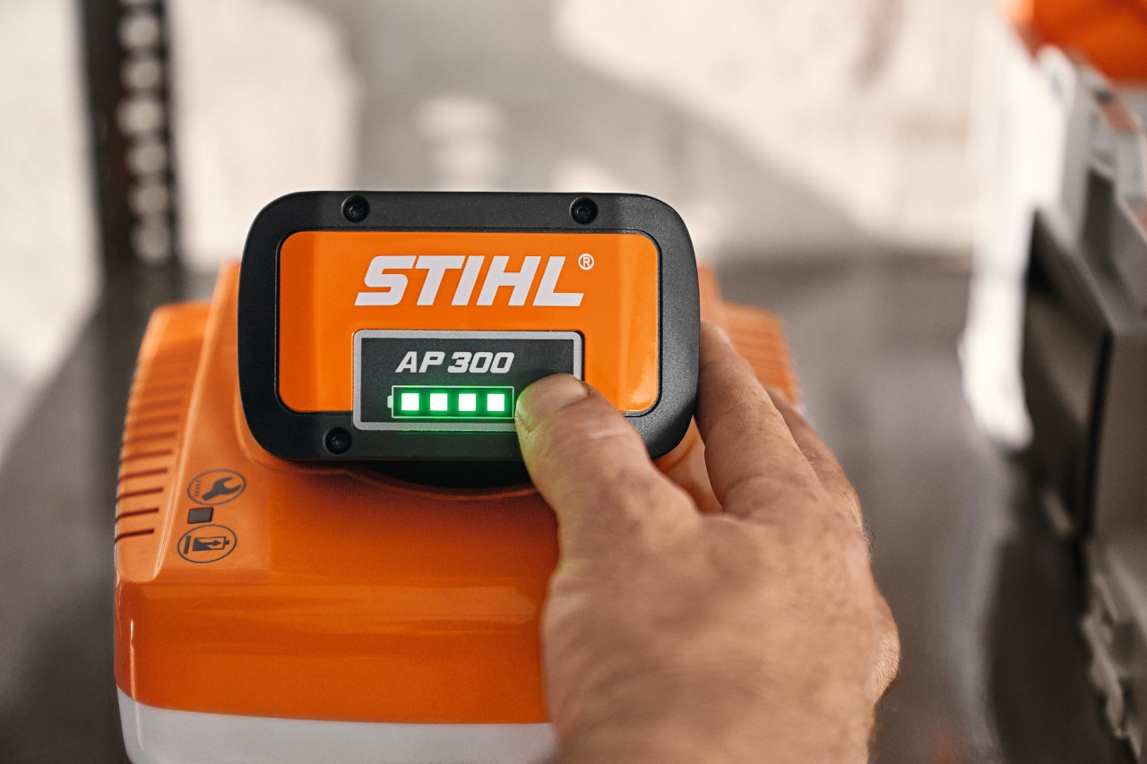 Zbliżenie osoby wskazującej na skrzynkę akumulatorową STIHL z podświetlanym wskaźnikiem 